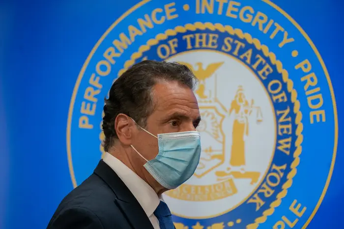 Governor Cuomo in a mask in front of NY State seal